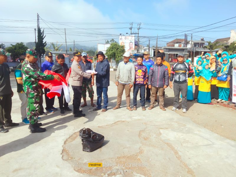 Caption : Kapolsek Cikajang bagikan bendera merah putih jelang HUT RI