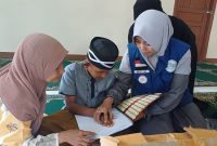 Elis Yanti Nurhayati Ketua GSJ Emak-emak Sukaraya Indah Bekasi saat memberikan bantuan Al-Qur'an Braille untuk Santri Ponpes Al-Muamalah Muhammad Farhan Fauzi 