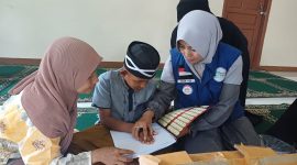 Elis Yanti Nurhayati Ketua GSJ Emak-emak Sukaraya Indah Bekasi saat memberikan bantuan Al-Qur'an Braille untuk Santri Ponpes Al-Muamalah Muhammad Farhan Fauzi 