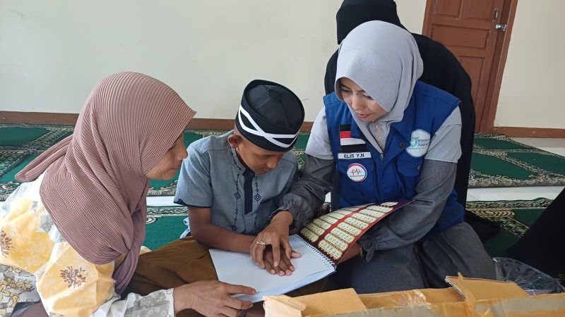 Elis Yanti Nurhayati Ketua GSJ Emak-emak Sukaraya Indah Bekasi saat memberikan bantuan Al-Qur'an Braille untuk Santri Ponpes Al-Muamalah Muhammad Farhan Fauzi 